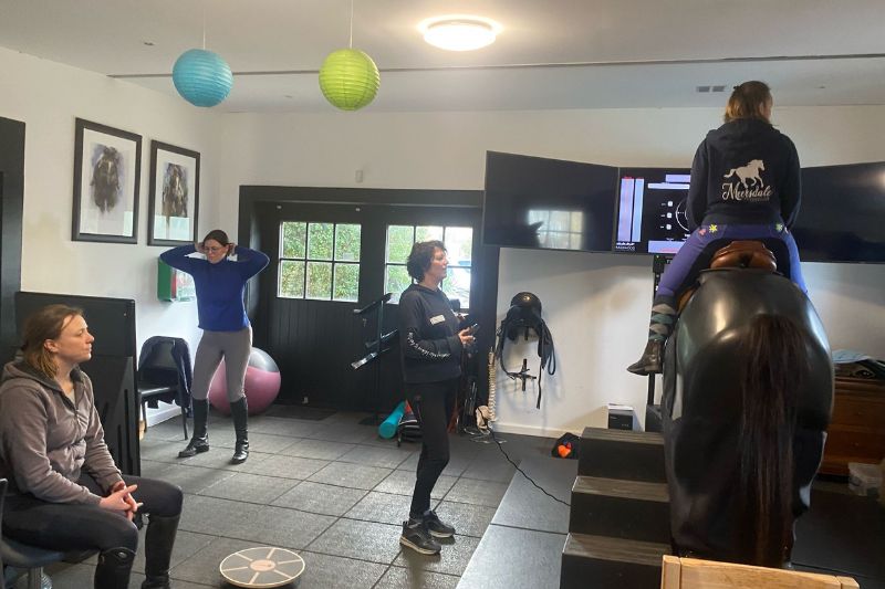 Amazone doet balansoefeningen zonder paard onder begeleiding van een trainer – ruiterfactor en vaardigheden ontwikkelen